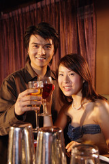 Couple holding drinks looking at camera