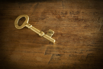 Old brass keys placed on a wooden floor low key light.