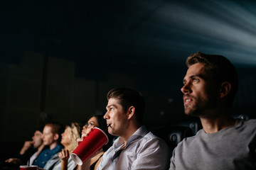 Young man watching movie with friends in cinema hall