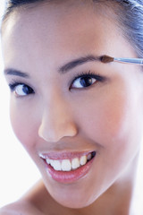 Headshot of woman using make-up brush