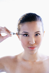 Fototapeta premium Woman holding mascara wand, looking at camera