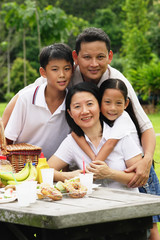 Family at picnic table, looking at camera