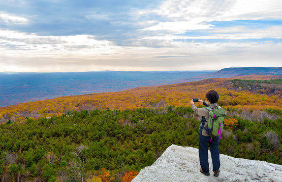 Mature asian woman hiking in autumn and taking picture of the view