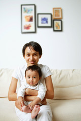 Fototapeta na wymiar Mother with baby boy, sitting on sofa, portrait