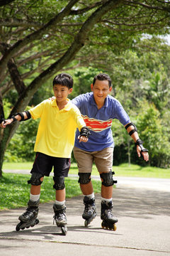 Father and son in park, on roller blades