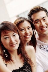 Two young women and one young man, looking at camera, smiling