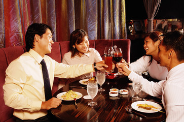 Couples sitting at restaurant, toasting with drinks across table