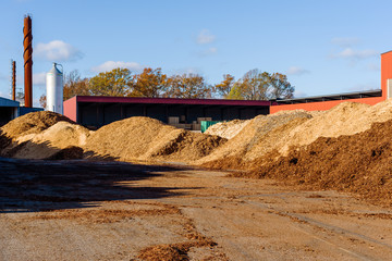 Large pile of biomass solid fuel in the form of medium sized wood chips. Industrial building in...