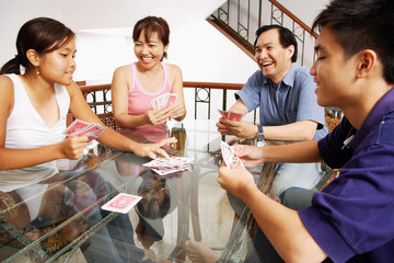 Family at home, playing cards around table