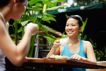 Two women at outdoor cafe, drinking coffee