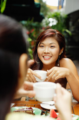 Two women facing each other holding coffee cups.