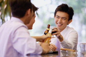 Young men at bar counter toasting with drinks