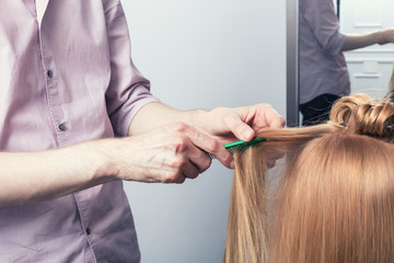 Obraz na płótnie Canvas A hairdresser making a haircut for a blonde girl. Selective focus