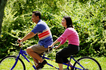 Couple in park, riding tandem bicycle