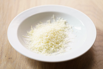 grated mozzarella on white plate closeup