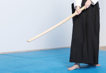 A girl in black hakama standing in fighting pose with wooden sword