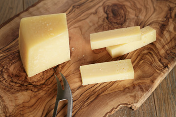 cutted parmesan cheese on olive cutting board