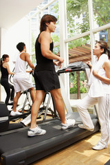 Fototapeta na wymiar Young adults in gym, walking on treadmill