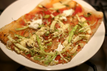 Vegetarian pizza on a plate, with tomato sauce, cheese, zucchini, leek and oregano, baked. Selective focus.