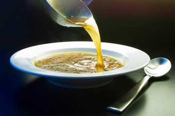 Ladle broth to the pan with the broth background top view  - obrazy, fototapety, plakaty
