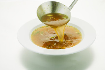 Ladle broth to the pan with the broth background top view 