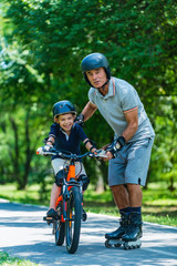 Obraz premium Grandfather teaching grandson how to ride a bike