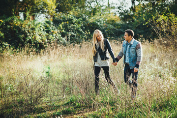 A young couple walking outdoors holding hands.