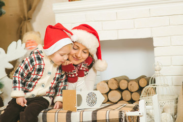 Happy mother and child boy in santa helper hats with gift box.