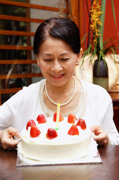Mature woman looking at birthday cake, smiling
