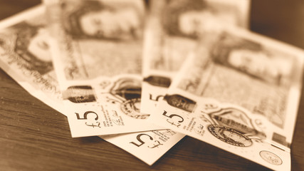 New Five Pound Notes on a wooden table E Sepia Tone Shallow Depth of Field, new polymer note, introduced in September 2016