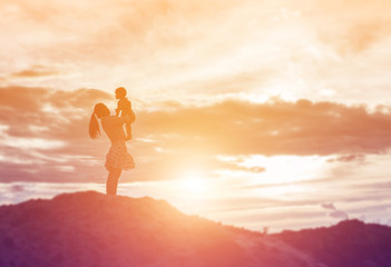 Fototapeta premium a silhouette of a happy young girl child the arms of his loving