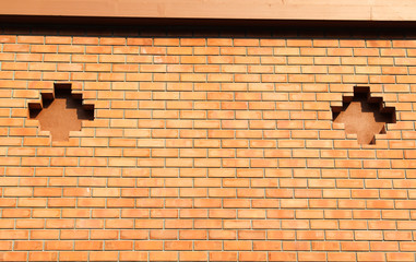 Orange brick wall with two holes.