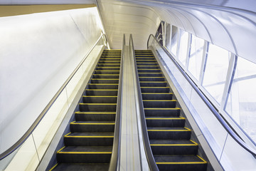 Empty escalator or moving stair. Also called stairway or staircase. Modern architecture design with step, glass for lift people up floor building i.e. shopping mall, airport, metro and subway station.