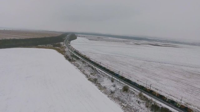 Aerial view of cargo train delivering goods, fuel, petrolium in winter. 4K.