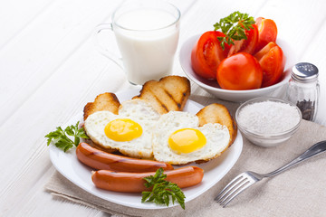 Breakfast on Valentine's Day - fried eggs in the shape of a heart and sausages.