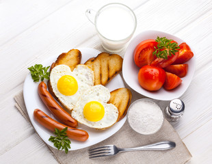 Breakfast on Valentine's Day - fried eggs in the shape of a heart and sausages. Top view