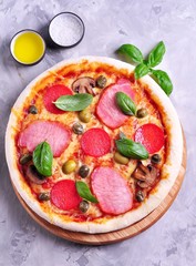 Homemade pizza with cheese, smoked meat, salami, mushrooms, olives and capers.