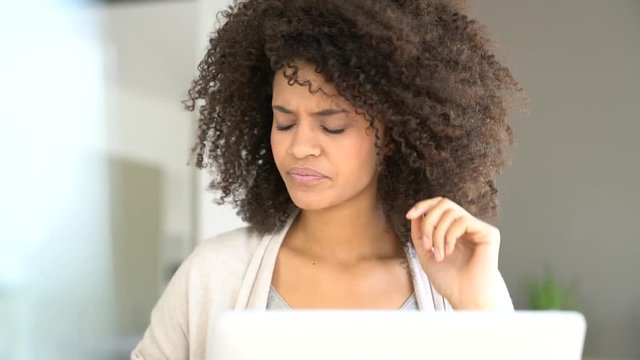 Mixed race woman having a headache working on laptop