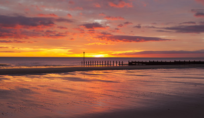 Obraz premium Dawn at South Beach, Blyth, Northumberland. Showing sunrise and groynes on sandy beach.