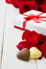 White gift box, roses and chocolate with heart shape on wooden table.copyspace

