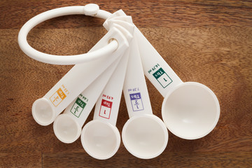 measuring spoons in varying sizes on wooden background
