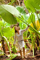 femme souriant qui marche dans la for&ecirc;t tropicale sous de grandes feuilles vertes