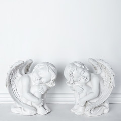 Statues of Sleeping Cupids on white background with copy space for text