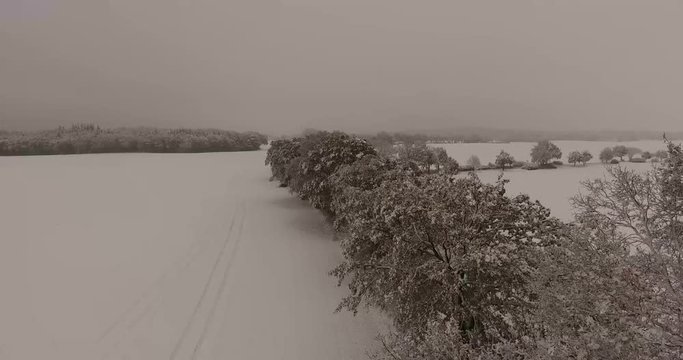 Low level flight over a rural Northern German landscape in winter with snow covered oak trees