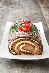 Chocolate yule log christmas cake with red currant isolated on white background.closeup
