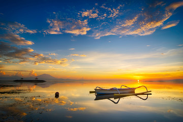 Fototapeta na wymiar Beautiful seascape sunrise scenery with golden sun at horizon and fisherman boat as foreground at Bali, Indonesia