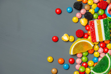 Colorful candies, jelly and marmalade over stone background. Top view with copy space