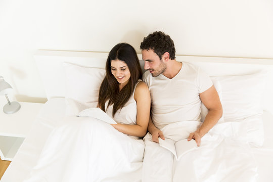 Couple with books in bed