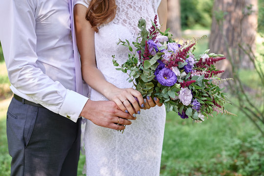 groom embracing bride with beautiful wedding bouquet