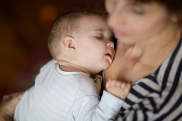 mother holds on hands of the sleeping baby